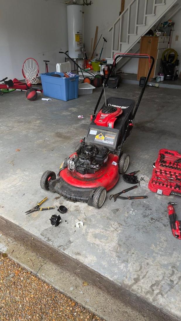 Red push mower in a garage during repair