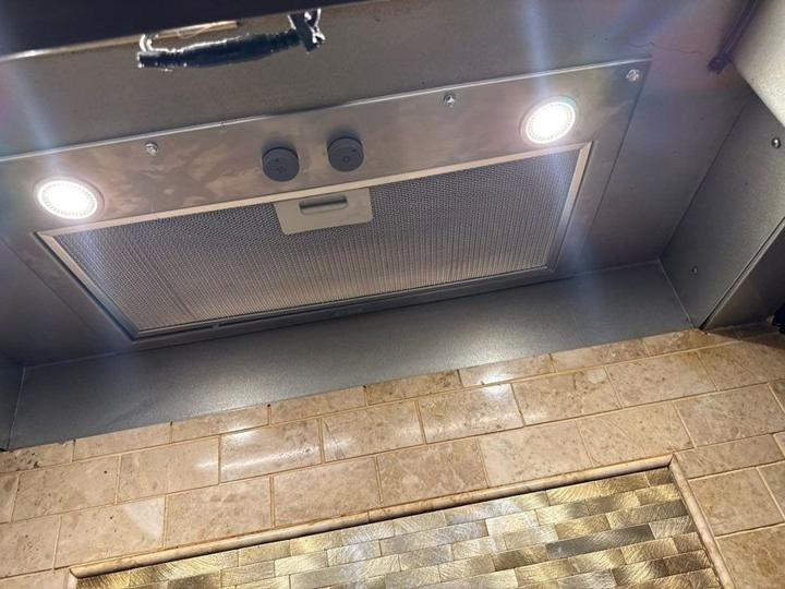 Range hood with lights above a tiled backsplash